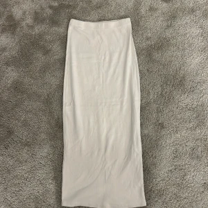 Ljusbeige långkjol i bomull - Säljer en stilren och enkel ljusbeige långkjol med rak passform. Kjolen är tillverkad i mjuk bomull och har en elastisk midja för extra komfort. Perfekt för dig som gillar minimalistisk och clean stil. Den är köpet i Missäy i Göteborg för flera år sedan, modellen finns därav inte kvar. Den når ner över knäna. Använd max 3 gånger.