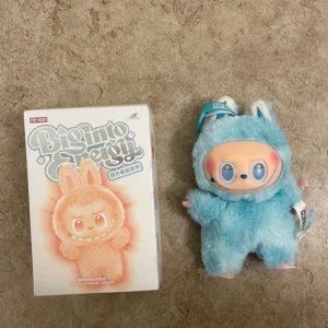 Pop Mart Biginto Energy Hope - Pop Mart Biginto Energy Hope figur, samlarobjekt i originalförpackning. Söt blå plyschdräkt med unikt ansikte, perfekt skick utan synligt slitage. Passar för samlare och dekoration, ej för barn under 15 år. Komplett med box och etikett.