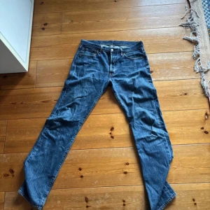 Levi's 501 blå jeans W33 L34 - Klassiska Levi's 501 jeans i blå denim med raka ben och normal passform. Snygga kontrastsömmar, fem fickor och ikonisk läderpatch bak i midjan. Perfekt för dig som gillar tidlös stil och vill ha ett par jeans som funkar till allt.