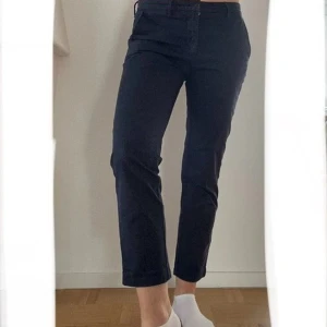 Mörkblå chinos Gant 38 - Blå stretchiga byxor i chinosmodell, lite ankelkorta i längden, i bomull (98%) och elastan (2%) från Gant.  Använda. Mycket fint skick.  Storlek 38. Mått: Innerbensöm 70 cm Längd ca 93-94 cm Över midja ca 42 cm Stuss ca 50 cm Grensöm fram ca 24 cm Grensöm bak till ryggslut ca 37 cm.