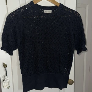 Mörkblå stickad topp Holly & Whyte - Supersöt mörkblå stickad topp från Holly & Whyte med korta puffärmar och ribbade kanter. Snyggt hålmönster över hela tröjan ger en luftig känsla. Perfekt till jeans eller kjol för en chill och trendig look. Den har legat i min garderob och aldrig använt den ‼️ Den ser jävligt mysig ut och kan nog bli en populär hitt bland dig som vill köpa den tröjan 🥰☺️
