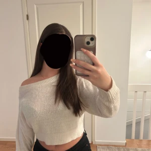 Vit croppad stickad tröja H&M Divided - Superfin vit croppad stickad tröja från H&M Divided med offshoulder-design. Tröjan har ribbad struktur och långa ärmar, perfekt för dig som gillar en chill och trendig look. Passar dig som vill ha en snygg och bekväm tröja med lite edge.