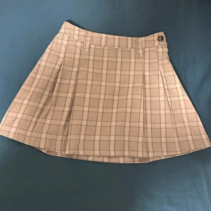 Beige rutig kortkjol - Beige kortkjol med rutigt mönster och snygga veck och en knapp i midjan