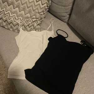 Svart och vit linnetopp  - Två stilrena linnetoppar från H&M i storlek S, en i svart och en i vit. Båda har smala axelband och ärmlös design, perfekta för att matcha med jeans eller kjol. Materialet är mjukt och stretchigt, vilket gör dem sköna att bära hela dagen.