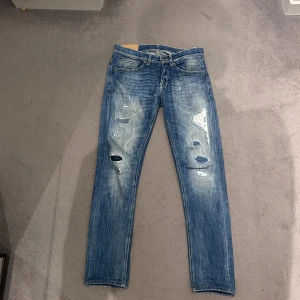 Dondup George jeans - Snygga blå  jeans från dondup (modell George) med slitna detaljer och slitningar på framsidan och på baksidan för en cool, avslappnad look. Klassisk femficksmodell med feta sömmar. Perfekt för dig som gillar dondup jeans. Hör av er vid frågor eller funderingar💭. Priset är ej hugget i sten 🪨!