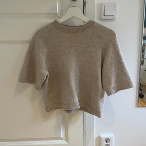 Beige stickad croppad tröja - Supermjuk och croppad stickad tröja i beige med korta ärmar och ribbad halsringning. Från & Other Stories, köpt för 500kr. 