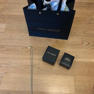 Silverhalsband från Maria Nilsdotter - Snyggt och stilrent silverhalsband från Maria Nilsdotter. Kedjan är tunn och elegant med en minimalistisk design, perfekt för dig som gillar klassiska smycken. Levereras i original ask och påse från märket.