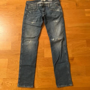 Replay Anbass - Snygga blå Replay Anbass jeans med slitna detaljer och lätt tvättad look. Klassisk femficksmodell med smal passform och normal midja. Priset är ej hugget i sten vid snabb affär. Tveka inte på att fråga! 33/32