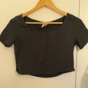 Svart croppad topp med kort ärm - En enkel svart croppad topp med rund halsringning och korta ärmar. Perfekt att matcha med höga jeans eller kjol för en clean och stilren look.