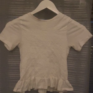 GINA TRICOT Ribbat volang t-shirt - En vit t-shirt från Gina Tricot storlek 134-140 men passar dom som är xs❤️