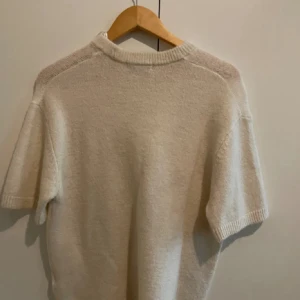 Vit stickad tröja Gina Tricot S - Vit stickad tröja från Gina Tricot i storlek S. Tröjan har korta ärmar och en rundad, ribbad halsringning. Mjuk och skön kvalitet som passar perfekt när du vill ha en enkel men stilren look. Premium Quality-kollektionen.