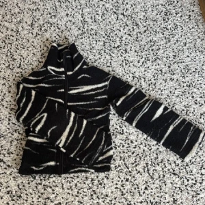 Svart teddyjacka med zebramönster XS - Säljer en svart teddyjacka i storlek XS med vit zebramönster, jackan är helt slutsåld och går inte att köpa på H&M hemsida. Jackan har hög krage, dragkedja framtill och är långärmad. Materialet är mjuk fleece. Perfekt nu till hösten 🍁❣️ 