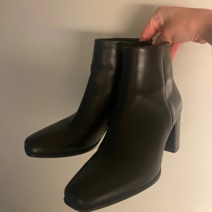 Svarta boots - Snygga svarta boots med hög klackTillverkade i slätt skinn med minimalistisk design och diskret dragkedja på sidan. Perfekta för dig som gillar stilrena boots med lite edge. De är mjuka, fina och bekväma. Användes ett fåtal gånger, i bra skick. Nypris 2000 kr