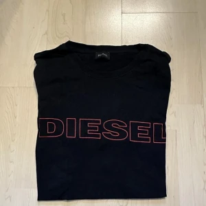 Diesel svart t-shirt - Svart T-shirt med röd "DIESEL" text på framsidan. Klassisk passform och rund halsringning.