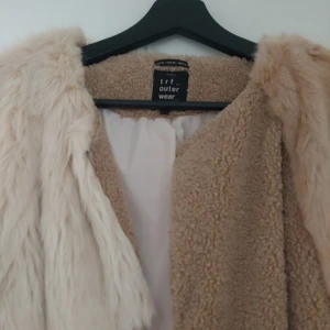 Beige och vit pälsjacka från Zara - Säljer en fluffig pälsjacka från Zara i patchwork-stil med olika nyanser av beige och vitt. Jackan har lång ärm och är tillverkad i fuskpäls och teddy-material för en riktigt cozy vibe. Perfekt för dig som vill sticka ut med en unik look!