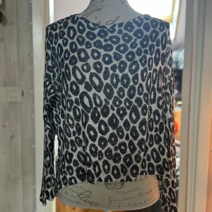 Leopardmönstrad tröja  - Säljer en snygg långärmad tröja  i storlek M. Tröjan är vit med svart leopardmönster och har en rak, lite loose passform. Materialet är mjukt och stickat, perfekt för dig som gillar att sticka ut lite extra.