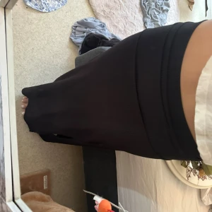 Svart ribbad långkjol med slits - Svart långkjol med ribbad struktur och en snygg slits framtill. Kjolen har en tight passform som framhäver figuren och är perfekt för dig som gillar en stilren och enkel. Obs finns lösa trådar