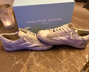 Philippe Model vita  - Storlek 41 men passar 42, priset kan diskuteras. Skorna har en stilren design med diskreta metalldetaljer och klassisk siluett, perfekt för dig som gillar exklusiva sneakers.