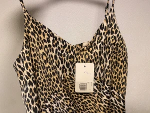 Helt ny Leopardmönstrad långklänning Levi's S - Snygg långklänning från Levi's i leopardmönster med tunna axelband och v-ringad hals. Klänningen har en figurnära passform och är tillverkad i ett mjukt, glansigt material som känns lyxigt mot huden. Perfekt för dig som vill sticka ut med en djärv look.