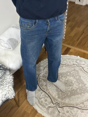 Levi's Stay Loose blå jeans - Säljer ett par Levi's Stay Loose jeans i klassisk blå färg. Modellen har en loose passform med raka ben och fem fickor. Jeansen har gul kontrastsöm och Levi's patch bak i midjan. Perfekt för dig som gillar avslappnad stil och bredare siluett.