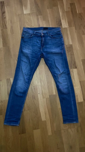 Blå slim jeans från Tiger of Sweden - Snygga blå jeans från Tiger of Sweden med klassisk femficksdesign och brunt läderpatch bak. Jeansen har skinny passform och är tillverkade i mjukt denimtyg med lätt tvättad look. Perfekta för dig som gillar stilrena och moderna jeans, Storlek 32/32 modell Evolve! Vid fler frågor eller funderingar tveka inte på att skriva!
