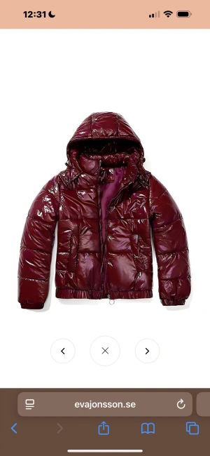 Glansig vinröd pufferjacka med huva från Eva Jonsson  - Säljer en helt nya jacka från Eva Jonsson då den inte passade. Prislapp och allt kvar. Storlek L men är mindre i storleken skulle säga ca M.