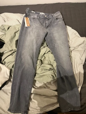 Grey denim jeans från Jack & Jones W31 L32  - Snygga oanvända grå jeans från Jack & Jones med klassisk femficksdesign och raka ben. Jeansen har en stilren tvättad look och är tillverkade i mjukt jeanstyg som sitter skönt. Nypris 799 w31 l32 regular fit 