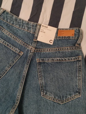 Raka jeans med revor 25/32 - Ett par raka blå jeans med revor på knäna. Från Cubus. Ord.pris 499kr. Jeansen är helt nya med prislapp kvar. Storlek 25/32.