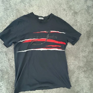 Mörkblå t-shirt från Jacob Cohën - Mörkblå Jacob Cohën T-shirt. Röd och vit på framsidan med Jacob Cohën tryckt över bröstet. Storlek M.