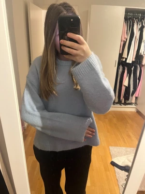 Ljusblå stickad tröja Gina Tricot - Mysig ljusblå stickad tröja från Gina Tricot i ullblandning. Tröjan har en loose passform med breda, långa ärmar och ribbade muddar vid hals, ärmslut och nederkant. Perfekt för dig som gillar oversized och chill stil.