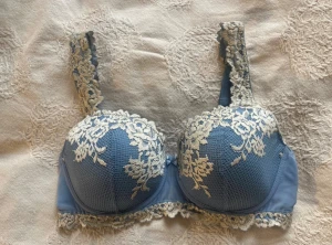 Blå bh med blommigt mönster - Supersnygg blå bh från intimissimi med krämvit spets och blommigt mönster över kuporna och axelbanden. Köptes för över 600:- super fint skick och unik färg 