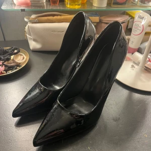 Svarta höga klackar - Svarta lack pumps med spetsig tå. Storlek 38, använd av mig på bal. Klacken är ca 10 cm hög. Väldigt bra skick!💕
