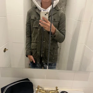 Grön jacka från J lindberg  - Snygg grön jacka från J Lindberg  med dragkedja och knappar. Jackan har flera praktiska fickor och en klassisk krage. Perfekt för höst och vår.