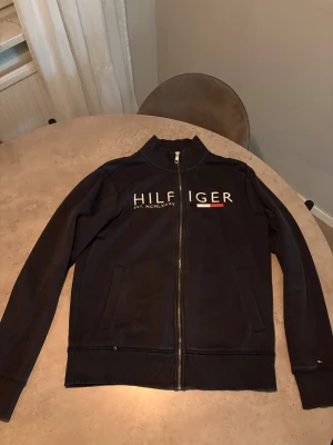 Svart zipjacka från Tommy Hilfiger - Snygg svart zipjacka från Tommy Hilfiger med logotyp.