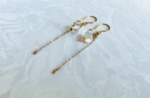 Guldiga örhängen med kristallpärlor - Snygga örhängen med tunn guldfärgad kedja och facetterade kristallpärlor som ger ett lyxigt och glittrigt intryck. Krokarna är också guldfärgade och designen är stilren med en modern touch. Perfekta för dig som gillar eleganta detaljer.