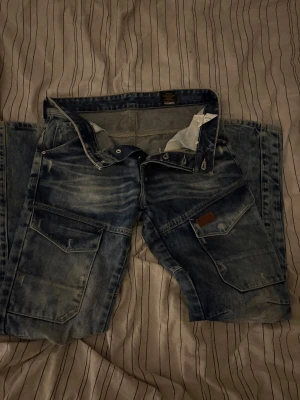 Blå cargopants från Voi Jeans - Säljer ett par blå cargopants från Voi Jeans med regular passform. Byxorna har slitna detaljer, stora fickor både fram och bak samt klassisk jeanslook. Perfekt för dig som gillar streetwear och funktionella byxor.