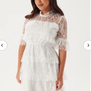 Vit spetsklänning med volanger - Säljer en superfin vit kortklänning i spets med flera lager volanger. Den kommer tyvärr inte komma till användning, prislappen sitter fortfarande på då den aldrig använts. Passar till studenten. 