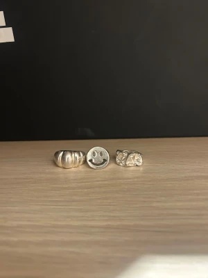 Tre coola silverringar med unik design - Säljer tre snygga silverringar. En är chunky med rundade former, en har en platt yta med ett smileyface och den tredje har en organisk, skulptural look. Perfekt för dig som vill ha statementringar med lite edge och personlighet. Man får köpa hur många man vill så priset kan diskuteras. Två är köpte på glitter och en på ophelia rings.