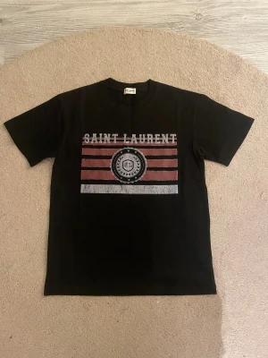 Saint Laurent T-Shirt - Tja säljer nu denna unika svarta t-shirten ifrån Saint Laurent i storlek XS för endast 799kr! Priset är ej hugget i sten! Skriv i dm vid funderingar eller fler bilder!🙌