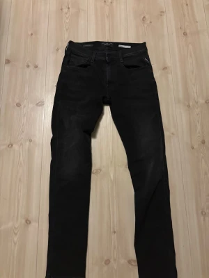 Replay Hyperflex svarta jeans - Svarta Replay Hyperflex jeans med slim passform och klassisk femficksdesign. Jeansen har en modern, rak siluett och är tillverkade i stretchigt jeansmaterial för extra komfort. Perfekta för dig som gillar stilrena och snygga svarta jeans.