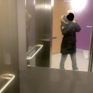 Svart Canada Goose jacka - Säljer en svart parkajacka från Canada Goose med ikonisk röd och vit logga på ärmen. Jackan har en stor huva med fluffig päls, praktiska fickor och lång passform som håller dig varm hela vintern. Perfekt för dig som vill ha en snygg och funktionell vinterjacka.