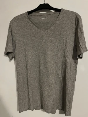 Grå v-ringad t-shirt Pier One - Enkel och stilren grå t-shirt från Pier One i mjuk bomull. T-shirten har v-ringning och korta ärmar, perfekt för en clean och avslappnad look. Passar dig som gillar basic plagg med snygg passform.