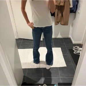 Blå bootcut jeans från Zara - Snygga blå jeans från Zara med klassisk bootcut passform och normal midja. Jeansen har fem fickor, gul kontrastsöm och är tillverkade i mjukt jeanstyg med lätt tvättad look. Perfekta för dig som gillar en retro vibe och vill ha lite utsvängda ben.