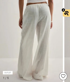 Vita vida linnebyxor med snörning - Luftiga och sköna vita linnebyxor med breda ben och dragsko i midjan. Byxorna har en avslappnad passform och är perfekta för varma dagar. Materialet är tunt och svalt, vilket ger en chill vibe. Passar dig som gillar en enkel och stilren look. Aldrig använda