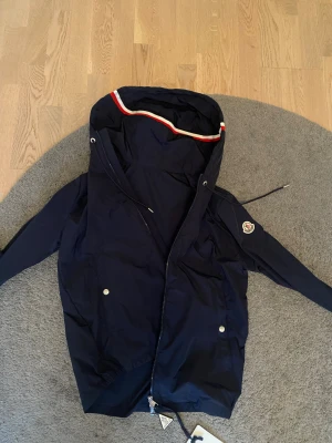 Moncler Vindjacka Marinblå - Marinblå Moncler Windbreaker. Storlek 1 (Motsvarar S). NFC scan fungerar. Tar ej emot byten och priset går tyvärr ej att diskuteras. Fråga gärna för fler bilder eller funderingar.