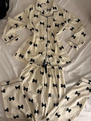 Pyjamassett - Ett jätte söt pyjamassett helt ny endast testad, den är cremefärgad med små gulliga rosetter. Setter består av byxor och skjorta