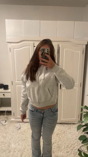 Ljusgrå kofta - Säljer en ljusgrå kofta med tjocka vita tråd, har en luva och kedja.