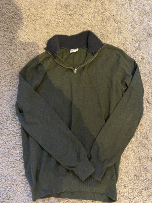 Mörkgrön half zip tröja John Henric - Snygg mörkgrön långärmad tröja från John Henric med ribbad krage i mörkare ton och half zip-dragkedja. Perfekt för dig som gillar stilrena och enkla plagg för vardag eller fest