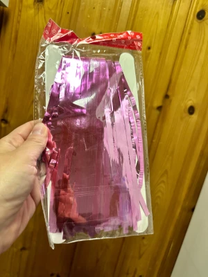 Rosa metallic girlang i plast - Säljer en glansig rosa girlang i metallic-look, perfekt som dekoration till fest eller kalas. Girlangen är tillverkad i plast och har långa, smala remsor som ger en cool effekt när den hängs upp. Kommer i originalförpackning.Ge ditt hem, din fest eller ditt event ett magiskt lyft med detta dekorativa girlang-draperi! Perfekt att hänga vid dörröppningar, längs väggar eller som en elegant backdrop till fotograferingar. Egenskaper: ✔️ Ca 2 meter långt och 1 meter brett ✔️ Lätt att sätta upp och ta ne