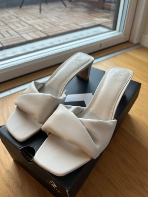 Beige klackskor från H&M - Beige klackar från H&M med fyrkantig tå och 2-3cm klack. Breda omlottband över foten, lätta att gå i. 